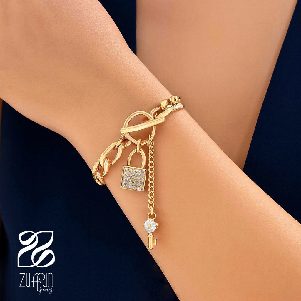 Gold bracelet with charms on a wrist against a dark background, featuring the brand 'ZUFFUN'.