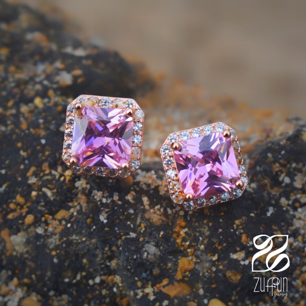 Pink square gemstone earrings on a textured surface with Zuffun branding.
