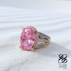 Pink gemstone ring with rose gold setting on a white sand background, Zuffun Jewelry logo visible.