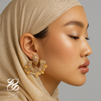 Close-up of a woman wearing gold earrings with a neutral background